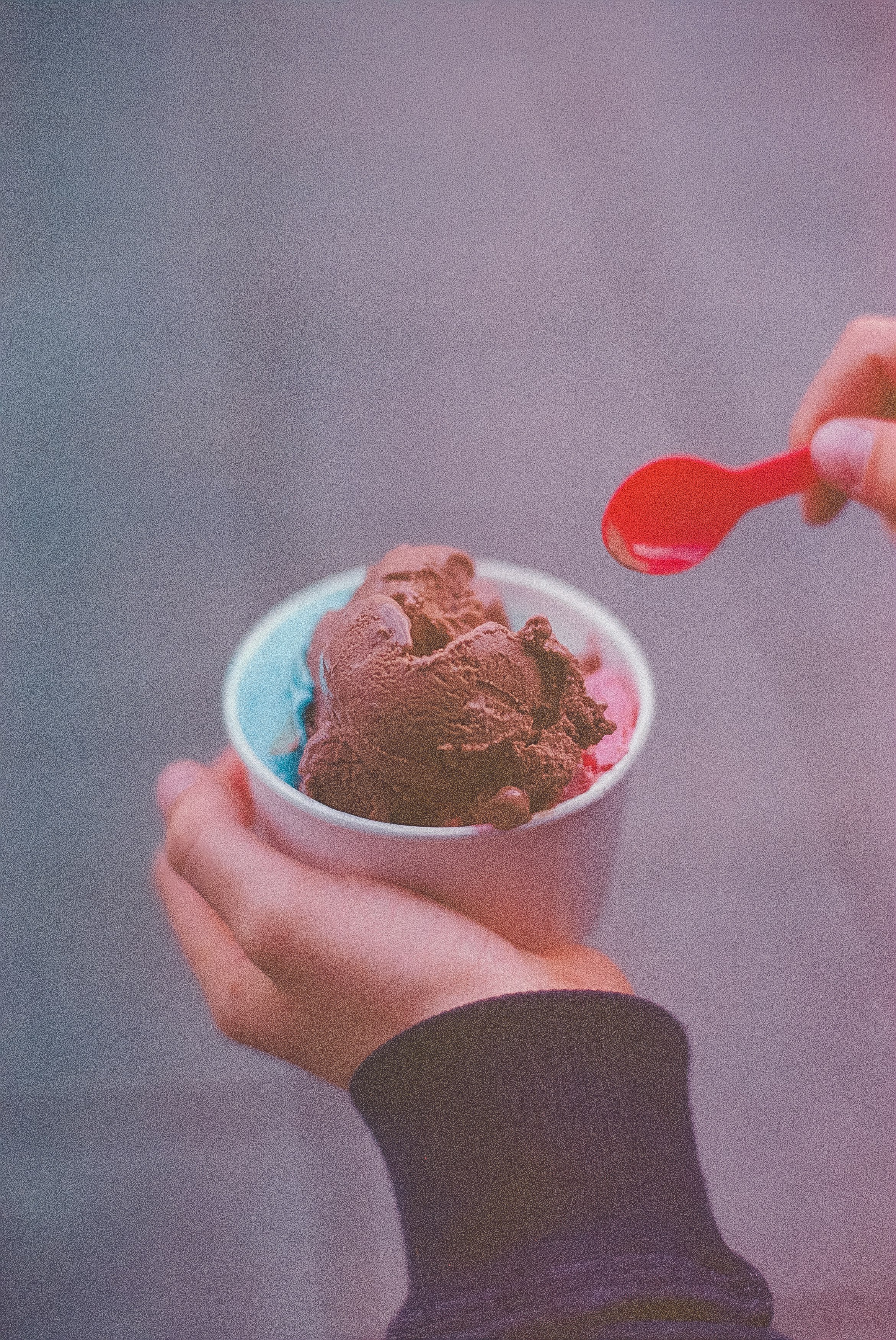 person holding ice cream with red spoon
